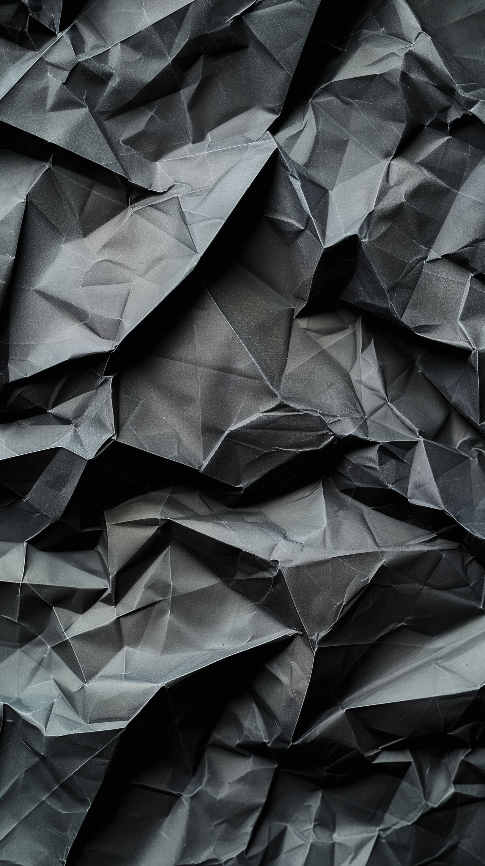 A close-up of crumpled black paper, showcasing intricate folds and shadows, creating a textured and abstract background suitable for an HD phone or iPhone wallpaper.